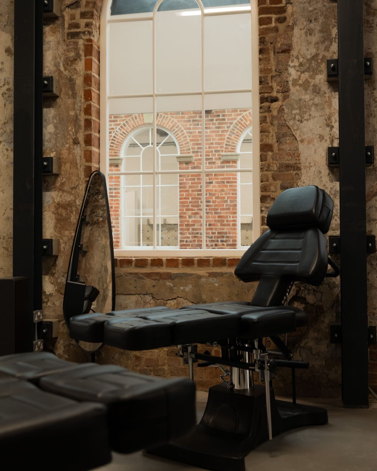 First White Cloth Hall — tattoo studio chair against exposed brick and arched window