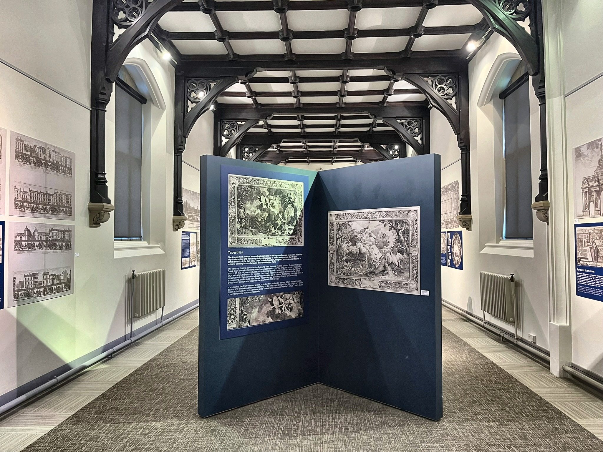 Free-standing display board showing tapestry-design engravings