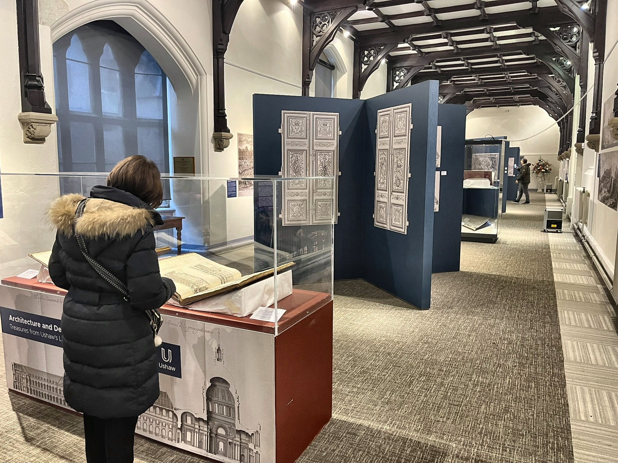 A visitor reading an open volume by the exhibition entrance